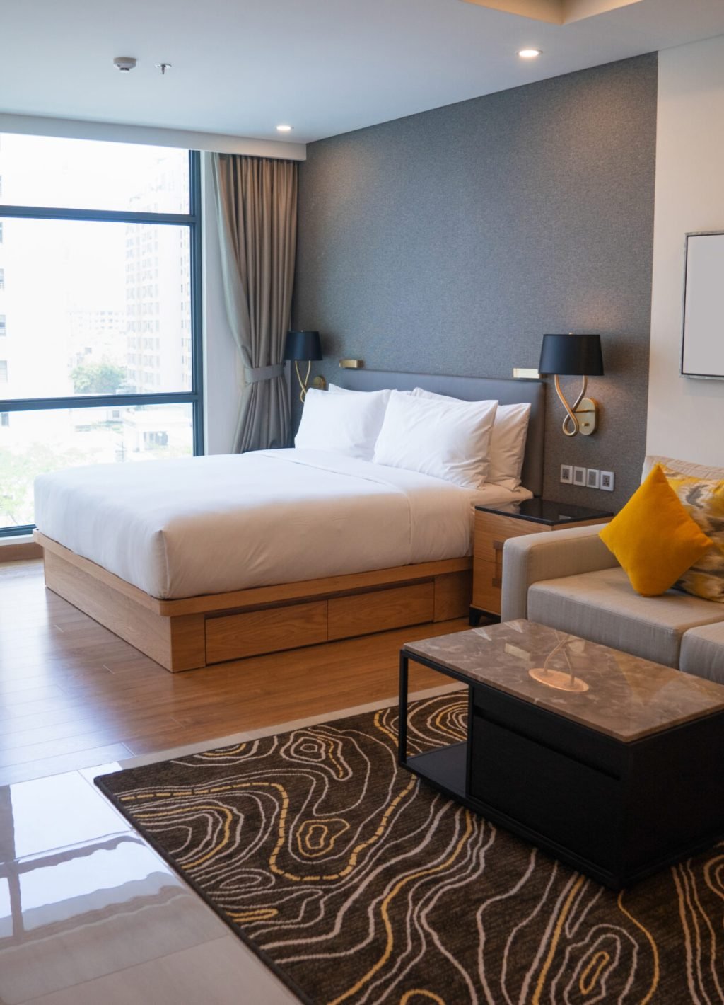 Modern studio apartment design with bedroom and living space. Hotel room panoramic window, king sized bed, couch and coffee table. City flat concept